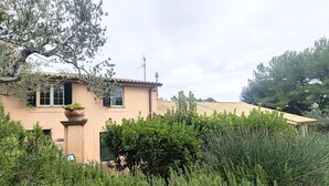 A house with a beige facade, a tiled roof, and a large window.