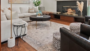 A modern living room with a fireplace, a sofa, a coffee table, and a TV mounted on the wall.