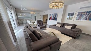 Un salon moderne avec un canapé d’angle, une table basse et un lustre.