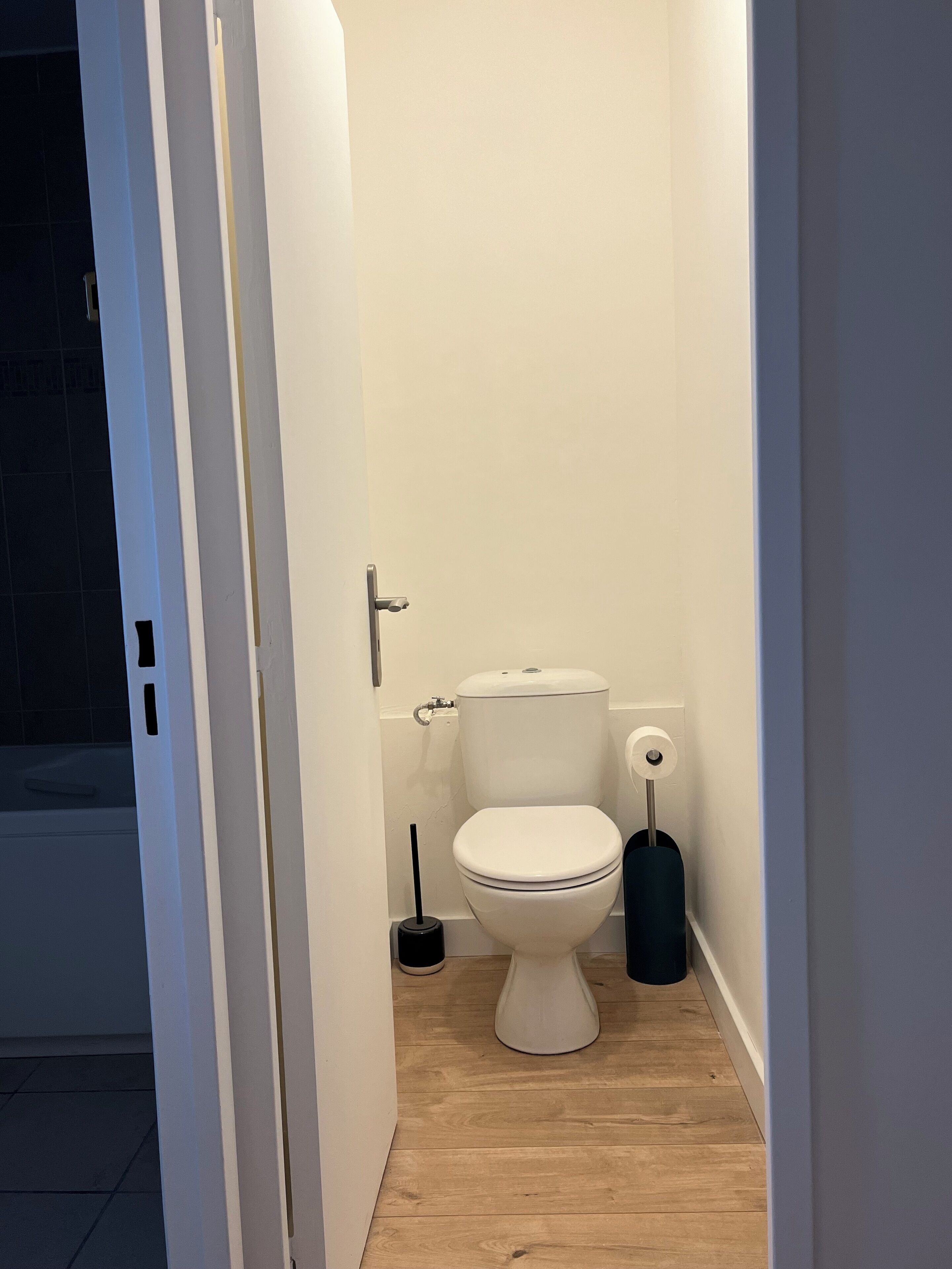 A small, clean bathroom with a toilet, a bidet, and a toilet brush.