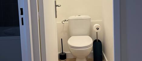 A small, clean bathroom with a toilet, a bidet, and a toilet brush.