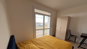 Ein Schlafzimmer mit Bett, Sessel, Schreibtisch und Kleiderschrank.