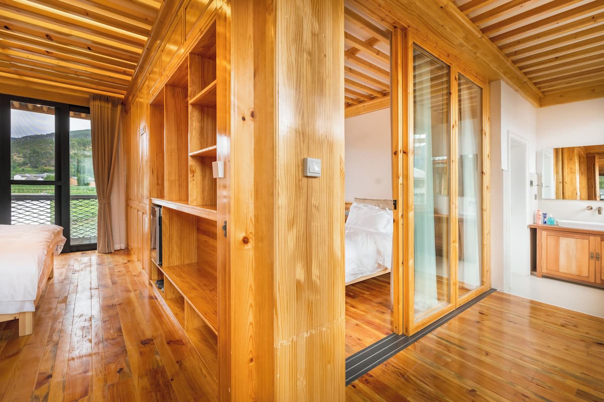 Un intérieur en bois comprenant un lit, une salle de bain et une vue sur l’extérieur, visible à travers une porte vitrée.