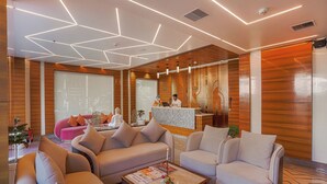Un hall moderno con una recepción, sofás y una mesa de centro.