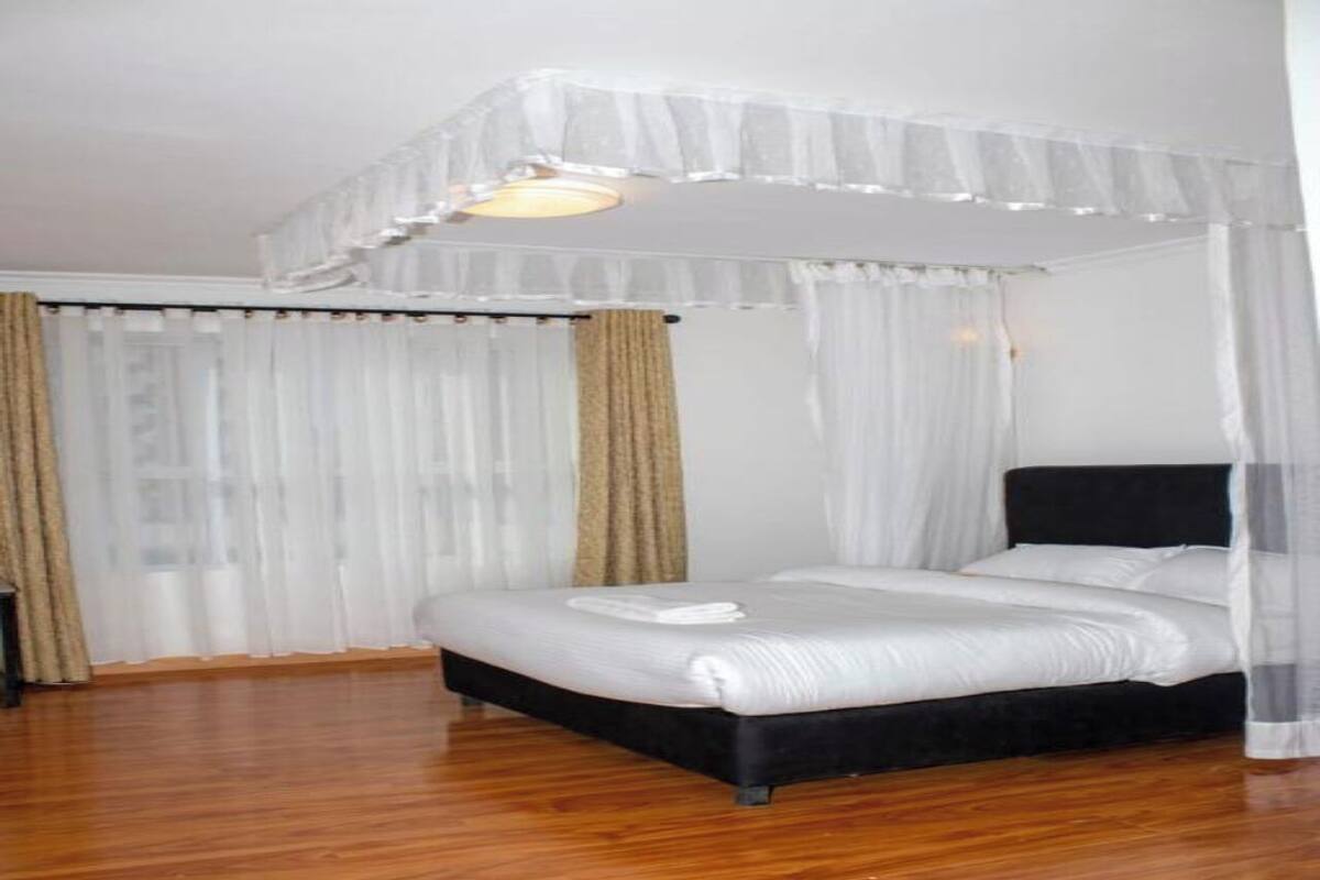 Une chambre à coucher avec un lit à baldaquin, du linge de lit blanc et des rideaux en voile léger.