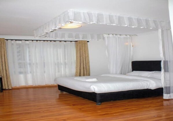 Un dormitorio con cama con dosel, ropa de cama blanca y cortinas de encaje.