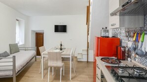 Un espace de vie compact comprenant un coin cuisine, un coin repas et un lit.