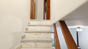 Un escalier en marbre avec des rampes en bois menant à une pièce dotée d’un ventilateur de plafond.