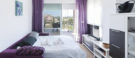 Une chambre d’hôtel moderne équipée d’un lit, d’un canapé, d’une télévision et d’un balcon avec vue.