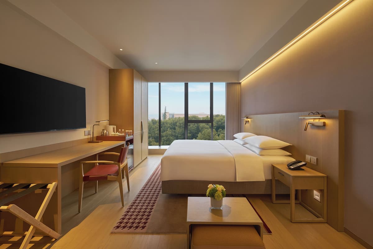 Een moderne hotelkamer met een groot bed, een bureau en een televisie.