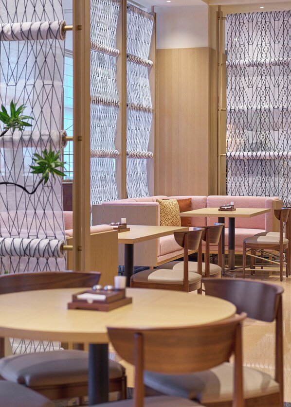 Un intérieur moderne comprenant un espace salon, des tables et des panneaux décoratifs.