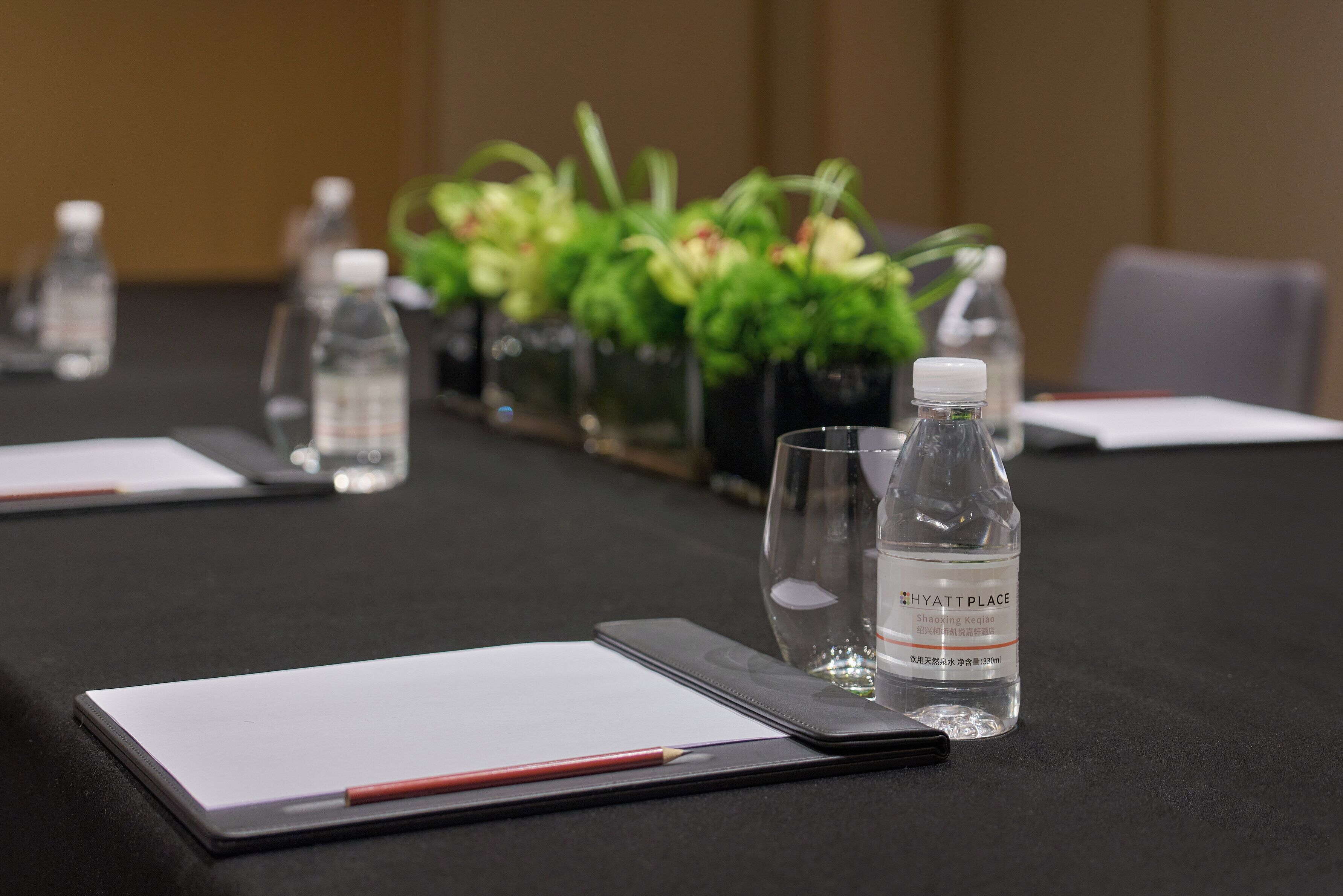 Una mesa de conferencias con botellas de agua, un vaso, un bloc de notas y un bolígrafo.
