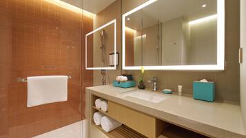 Un baño moderno con un espejo grande, un lavamanos y una cabina de ducha de vidrio.