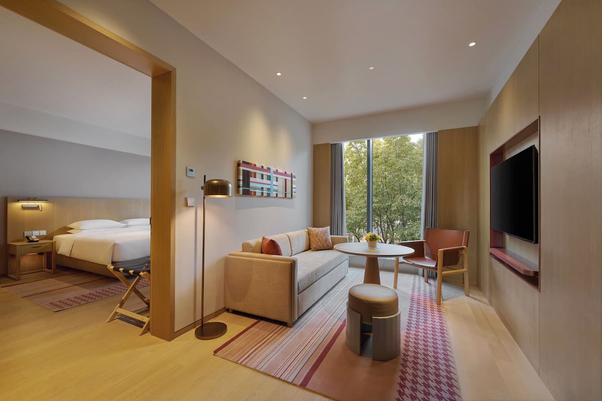 Een moderne hotelkamer met een bed, bank, rond tafel en televisie.
