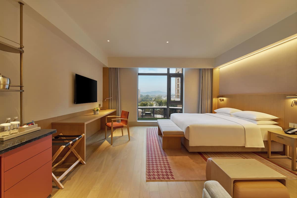 Een moderne hotelkamer met een groot bed, een bureau, een stoel, een televisie en uitzicht op de stad.