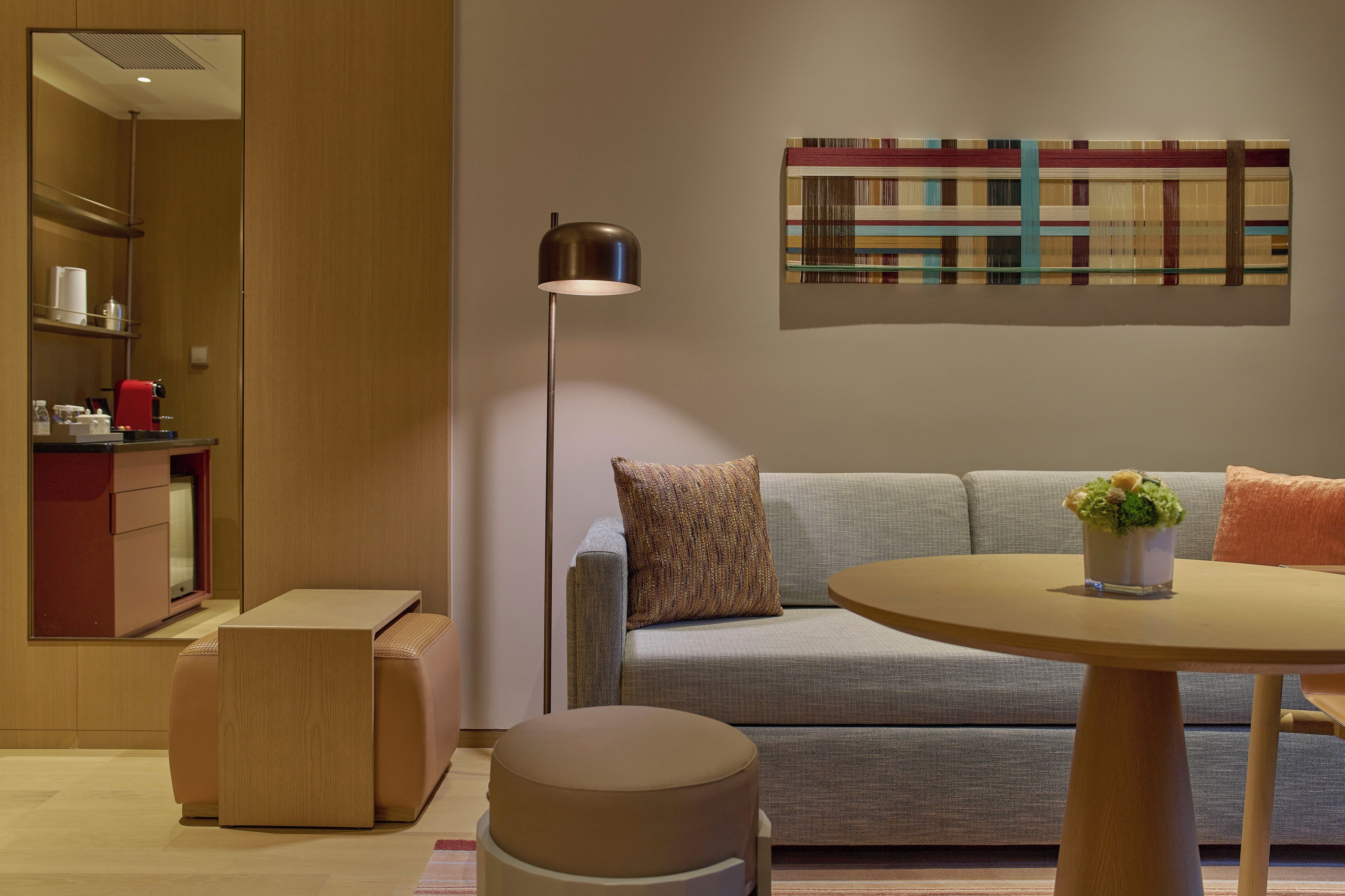 Un salon moderne avec un canapé, une table ronde, un lampadaire et une machine à café.