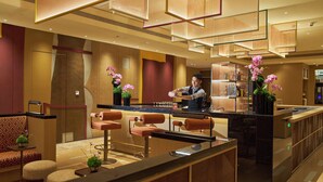 Un hall d’hôtel moderne comprenant un comptoir d’accueil, un espace salon et un bar.