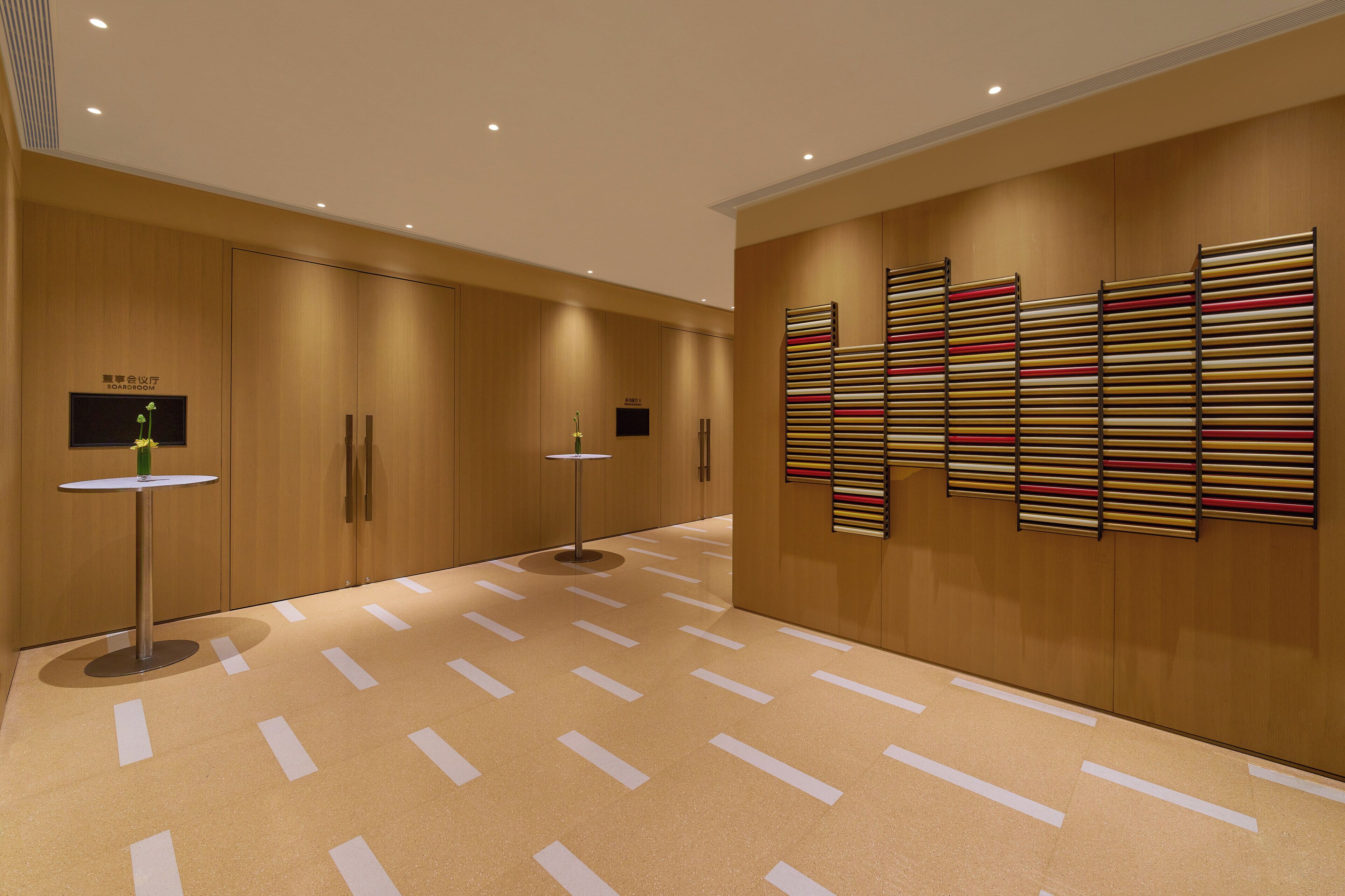 A modern hallway with wooden paneling, a patterned floor, and a wall-mounted art piece.