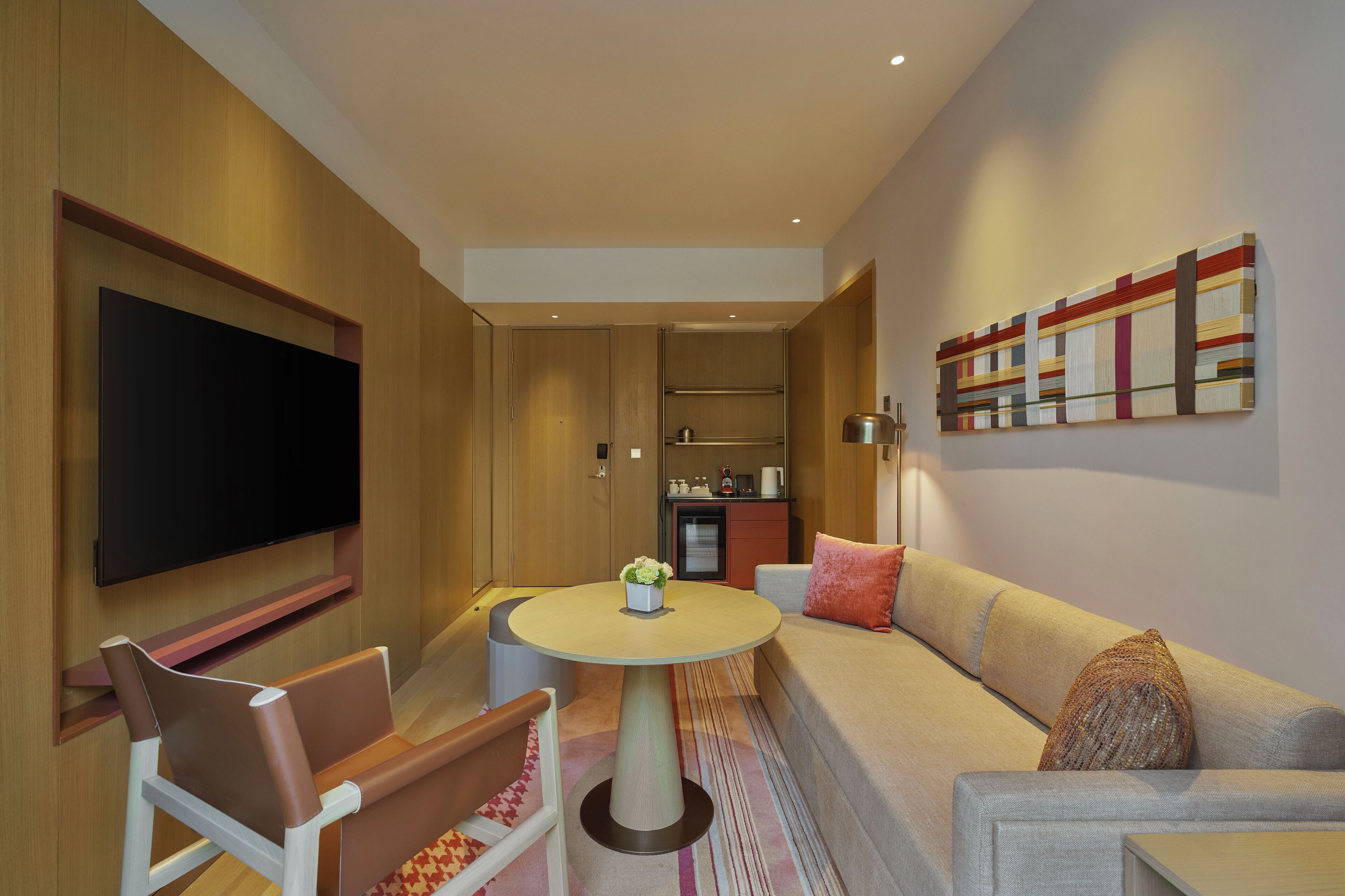 A modern living room with a flat-screen TV, a round coffee table, a sofa, and a small cabinet.