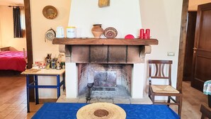 Un salón acogedor con chimenea, una repisa de madera y una alfombra azul.