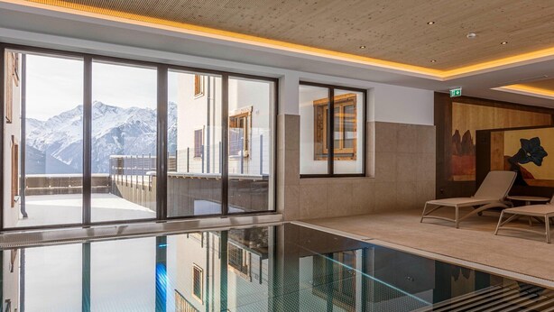 A modern indoor pool area with large windows, a glass floor, and lounge chairs. - Studio near the slopes with wellness area (Mittersill)