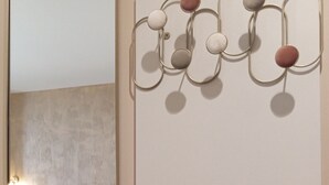 Et moderne soveværelse med en seng, et spejl og en vægmonteret lampe.