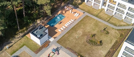 Vue aérienne d’un quartier résidentiel avec une piscine, des chaises longues et un terrain de jeux.