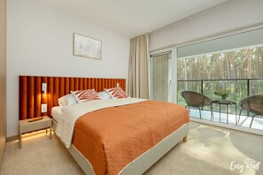 Relax in a spacious room with a large bed, a bedside table, and a balcony offering a forest view.