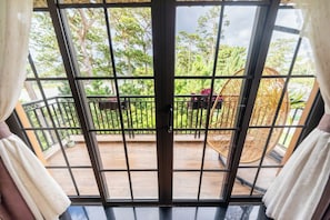 A balcony with a view of a garden and a wicker chair. - Khai Ngoc Hotel (Xuan Huong - Da Lat)