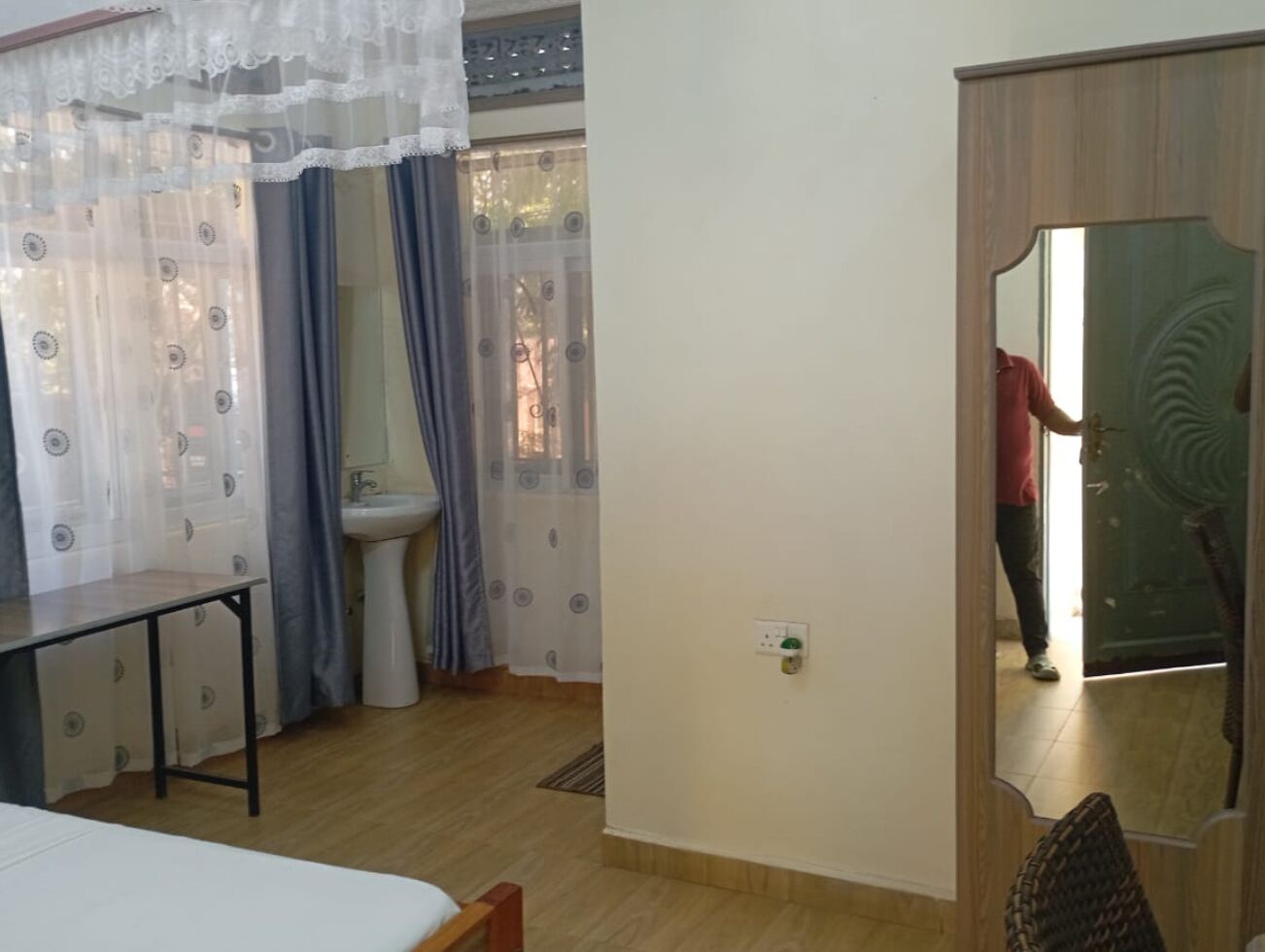 Una stanza con un letto, un tavolo, un lavandino e uno specchio.