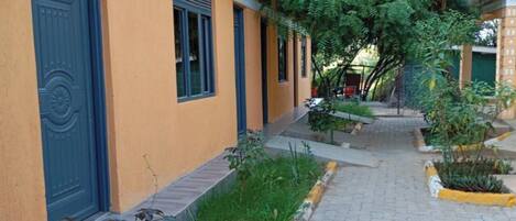 A building with a blue door and windows, a paved pathway, and greenery.