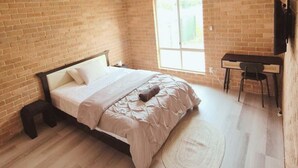 Un dormitorio con una cama, un escritorio y una silla.