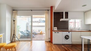A modern kitchen with a washing machine, a dining area with yellow chairs, and a sliding glass door leading to a balcony. - Alhóndiga Ático. 1-bedroom, private terrace (Sevilla)