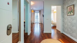 A hallway with wooden flooring, a door with a keyhole, and a framed picture on the wall.