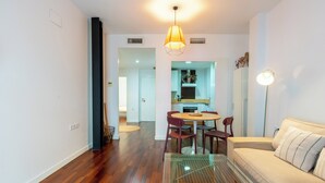 A modern living room with a glass coffee table, a sofa, and a dining area with chairs.