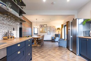 Una cucina moderna con pavimento a spina di pesce, una zona pranzo con tavolo e sedie in legno e un frigorifero integrato.