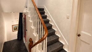 A staircase with wooden handrails and dark carpeted steps, leading to a white door. - Thistle Do Nessly, Inverness (Inverness)