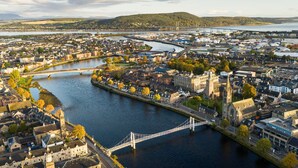 A river flowing through a town with a bridge, historic buildings, and a hilly landscape in the background. - Thistle Do Nessly, Inverness (Inverness)