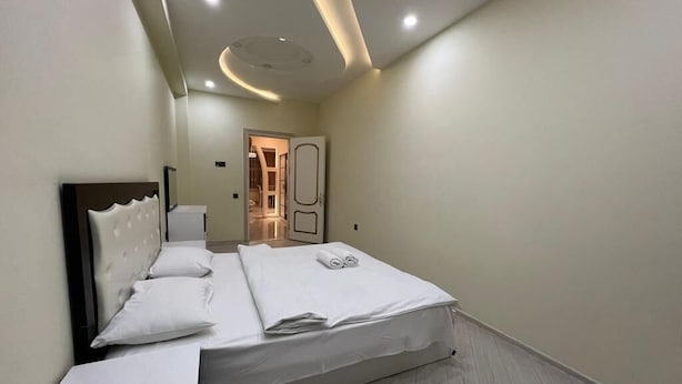 A modern bedroom with a large bed, a bedside table, and a ceiling with recessed lighting. - Victory Park Apartments (Baku)