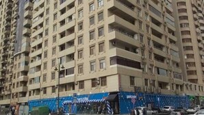 A high-rise residential building with multiple balconies and a ground-level commercial area. - Victory Park Apartments (Baku)