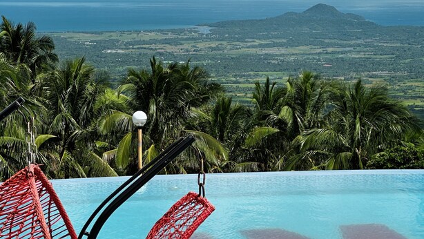 Ein Pool mit Blick auf eine Berglandschaft und Palmen.