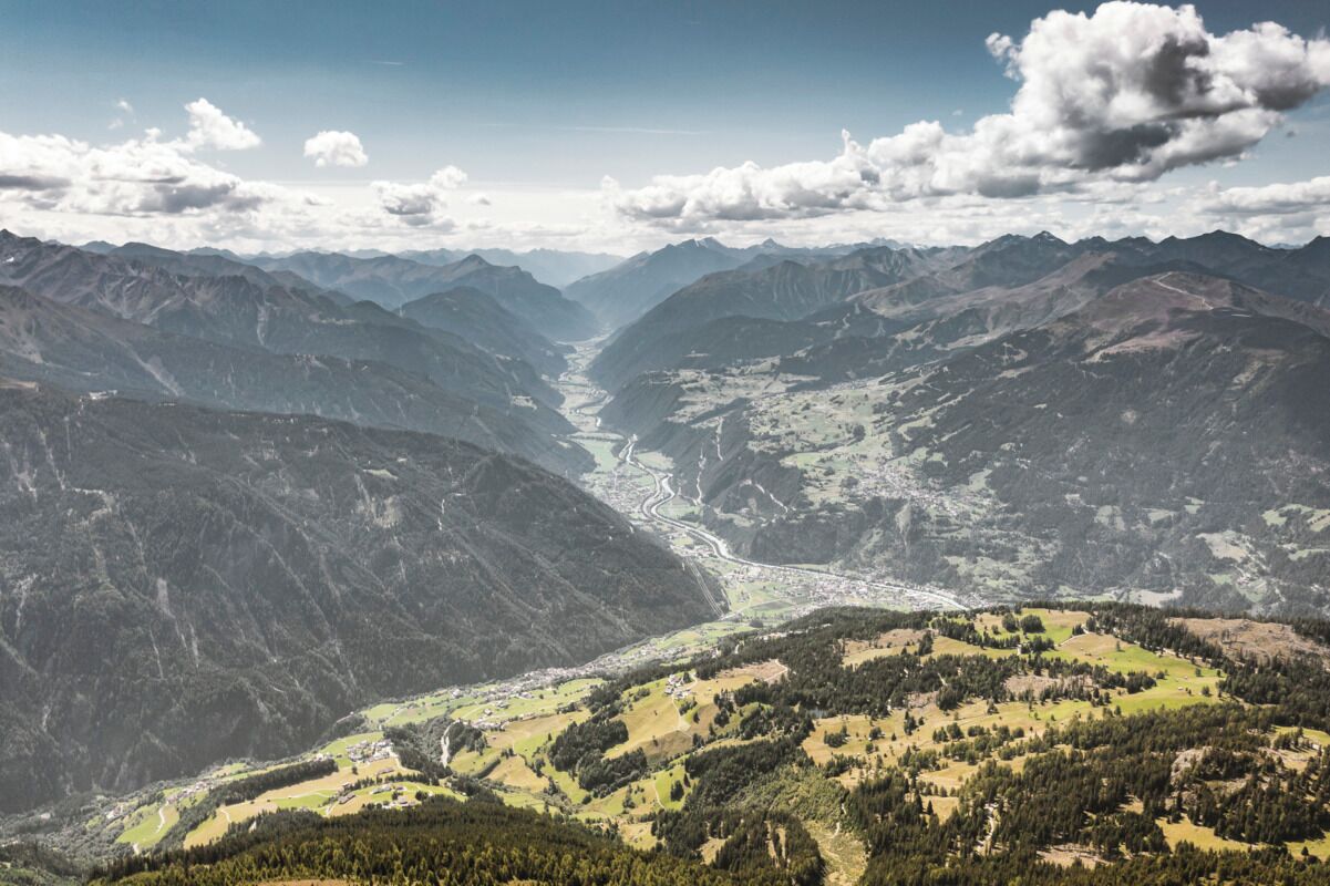 Paisaje montañoso con un valle, carreteras y edificios dispersos.