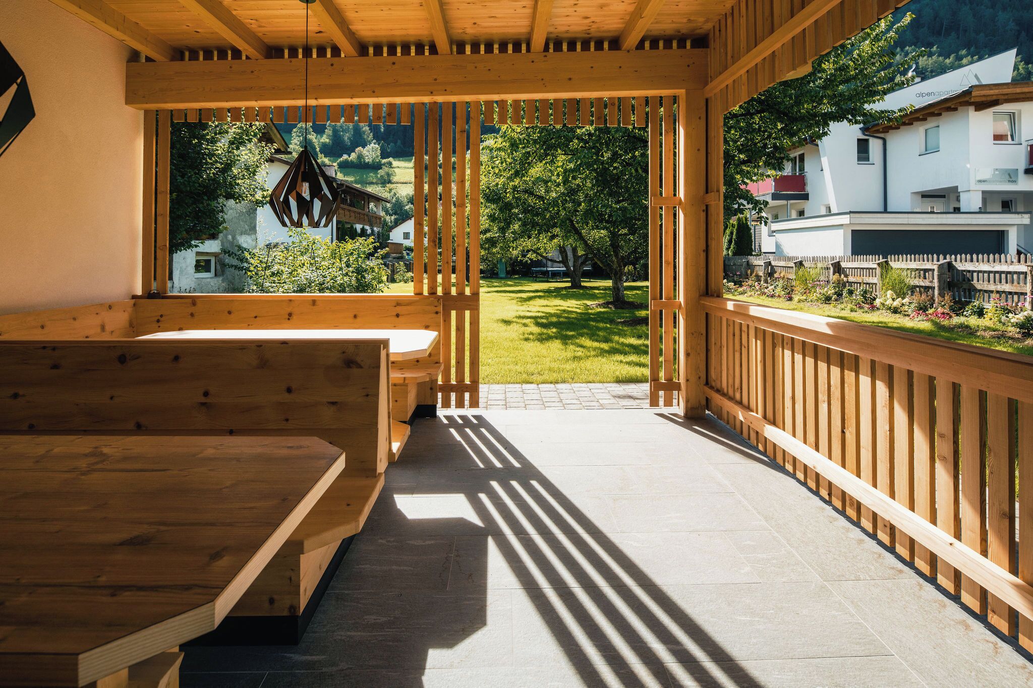 A wooden deck with a bench and a view of a green landscape and buildings.