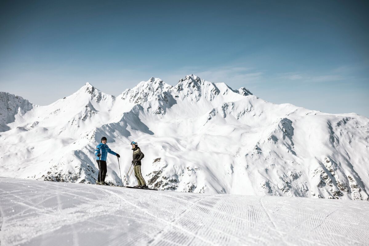 Un paysage de montagne enneigé avec deux skieurs.