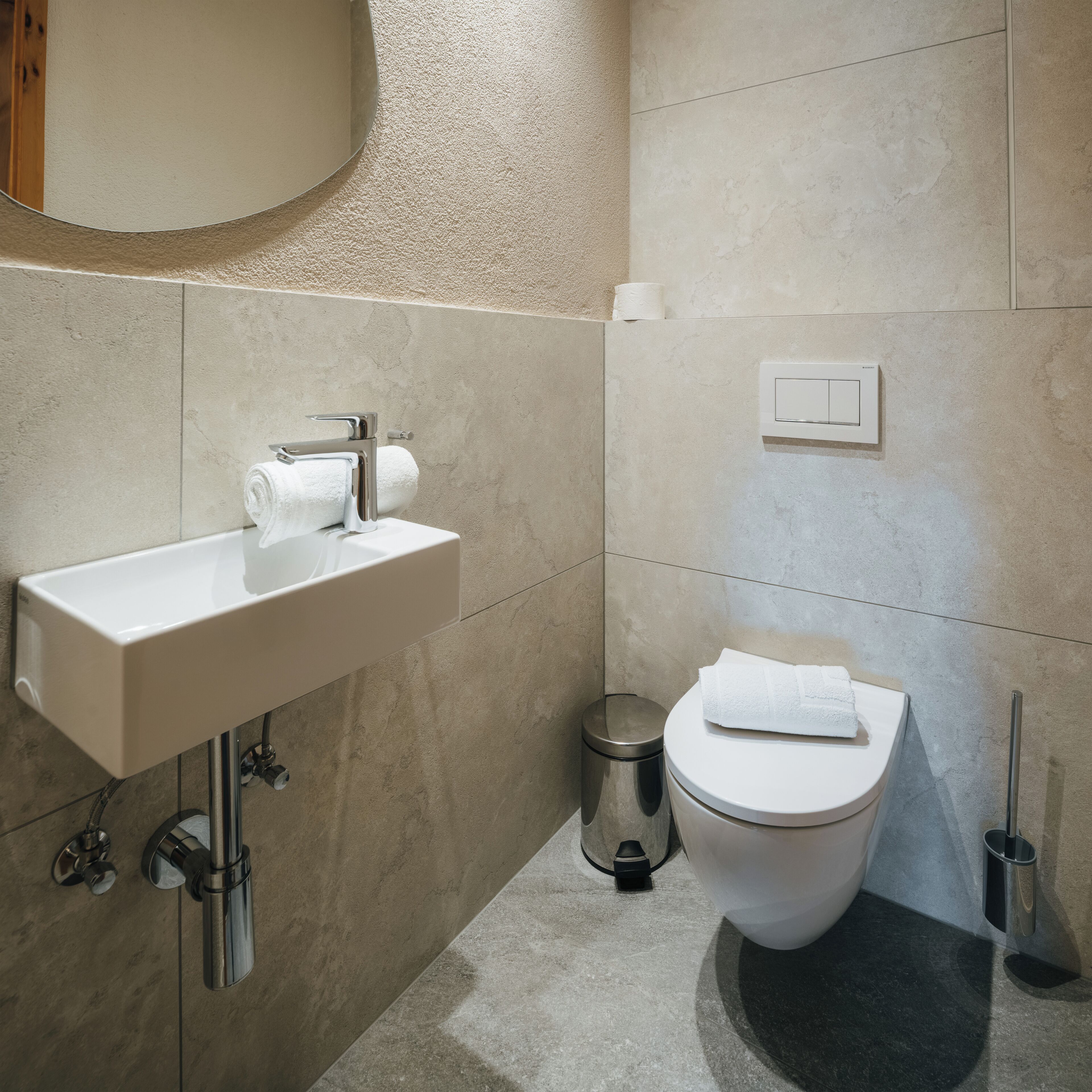 Une salle de bain avec un lavabo blanc, des toilettes et une poubelle.