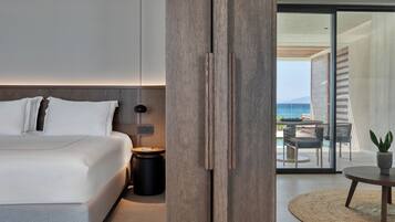 A modern bedroom with a large bed, a bedside table, and a view of a balcony with outdoor furniture.
