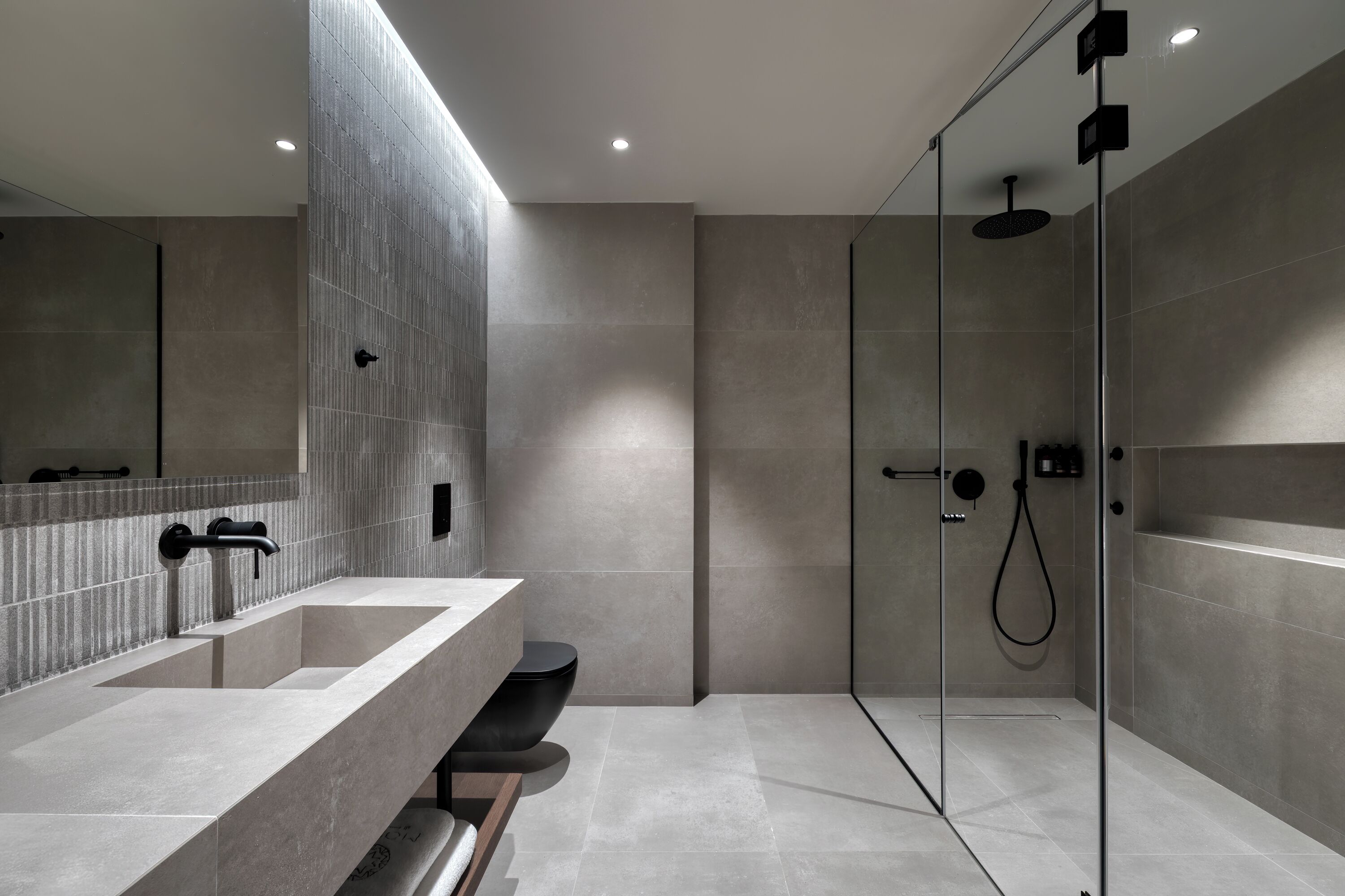 Un baño moderno con un espejo grande, dos lavamanos, una ducha y zona de ducha con mampara de vidrio.