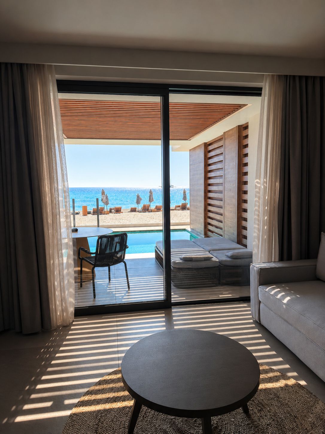 Una habitación moderna con puerta de cristal que da a una piscina y vista al mar.