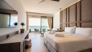 A modern hotel room with a large bed, a desk, and a balcony with a view of the sea. - Mosay All Suite Hotel - Adults friendly (Kos)