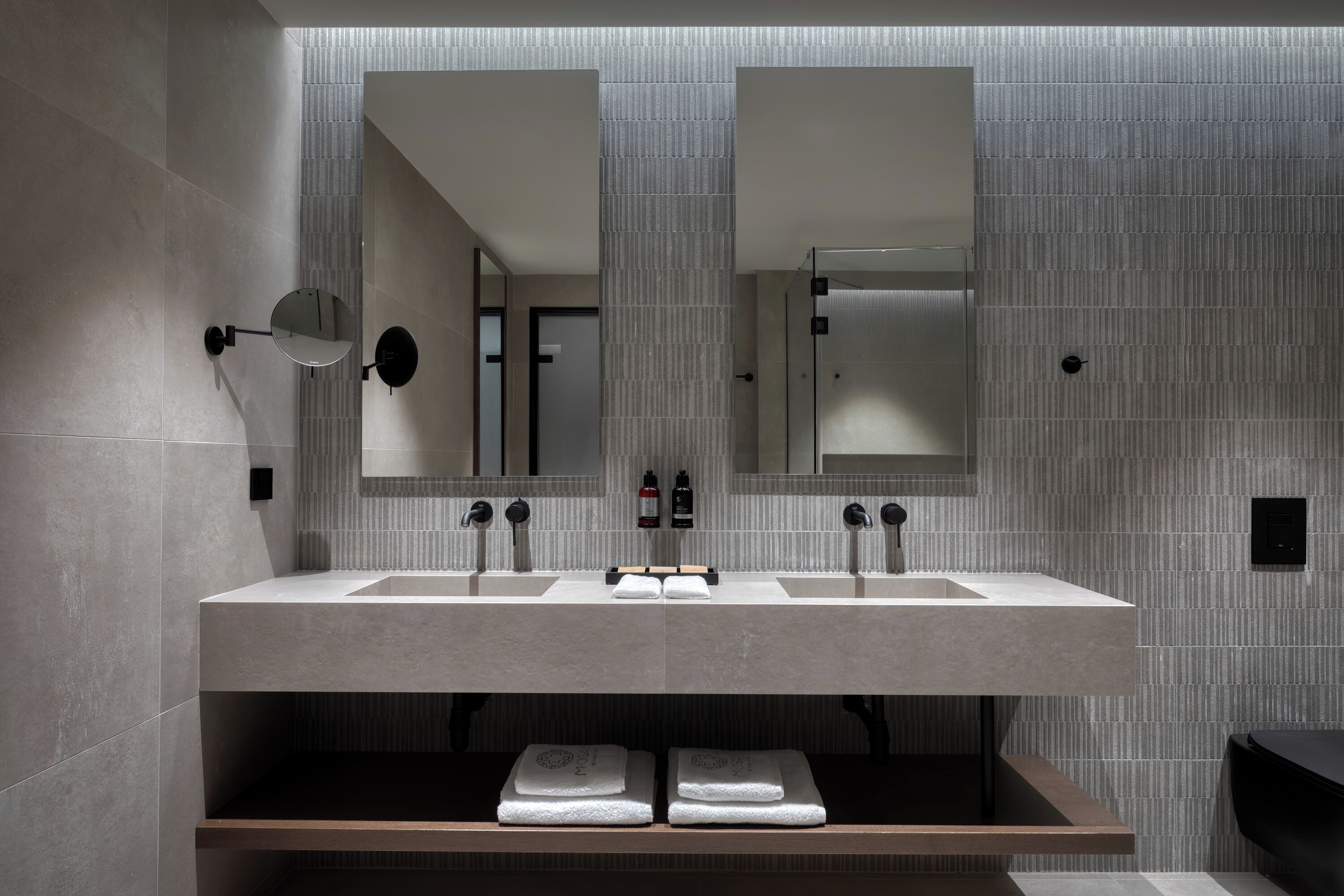 Un baño moderno con dos lavamanos, espejos amplios y un perchero para toallas.